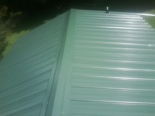 New green metal panels meeting at the ridge of a roof — Flat Roof Repair work by our crew in Bryce