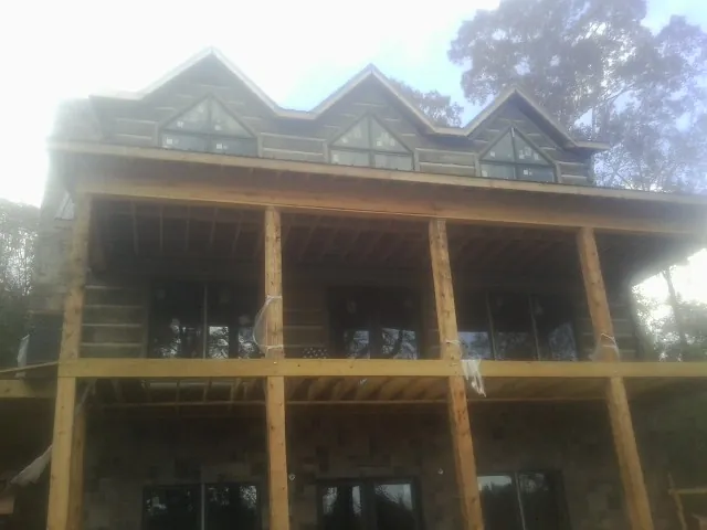 Dormers and porch framing on a large log home under construction — Roof Coating work by our crew in Bryce