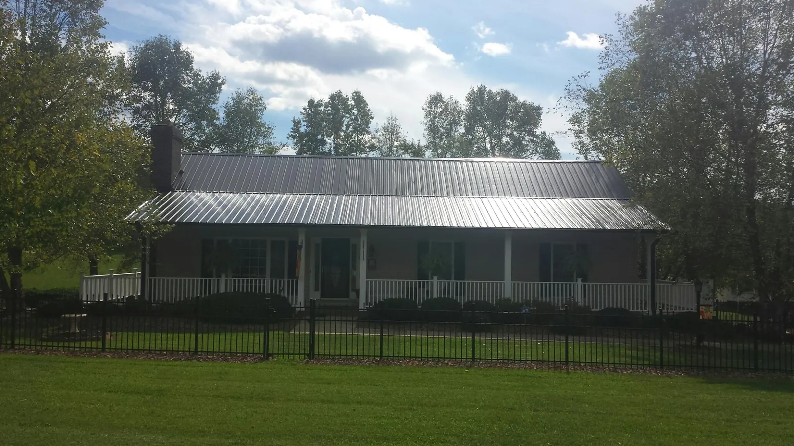 Gray metal roof on a brick ranch with a full width front porch — Gutter Guard Installation work by our crew in Bryce