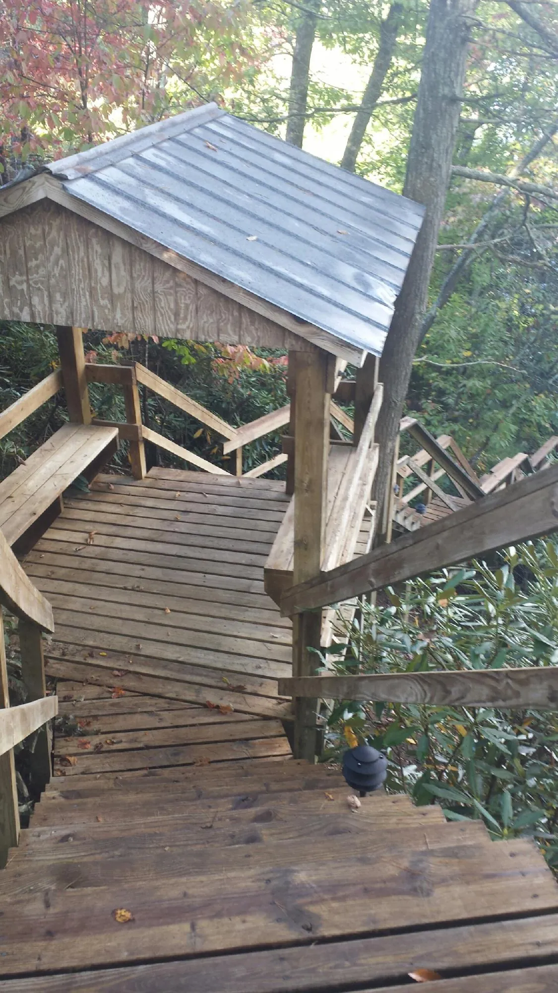 Metal roofed shelter over wooden steps on a wooded walkway — Skylight Repair & Installation work by our crew in Bryce