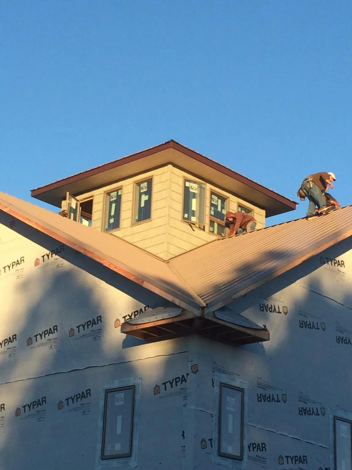Roofers working around a rooftop cupola on a new metal roof at sunset — Roof Waterproofing in Bryce by Roofing Brothers